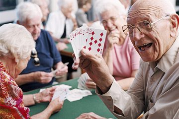 a senior man holding up a hand of cards