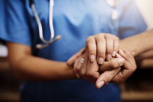 A close up of a nurse holding a patient’s hand