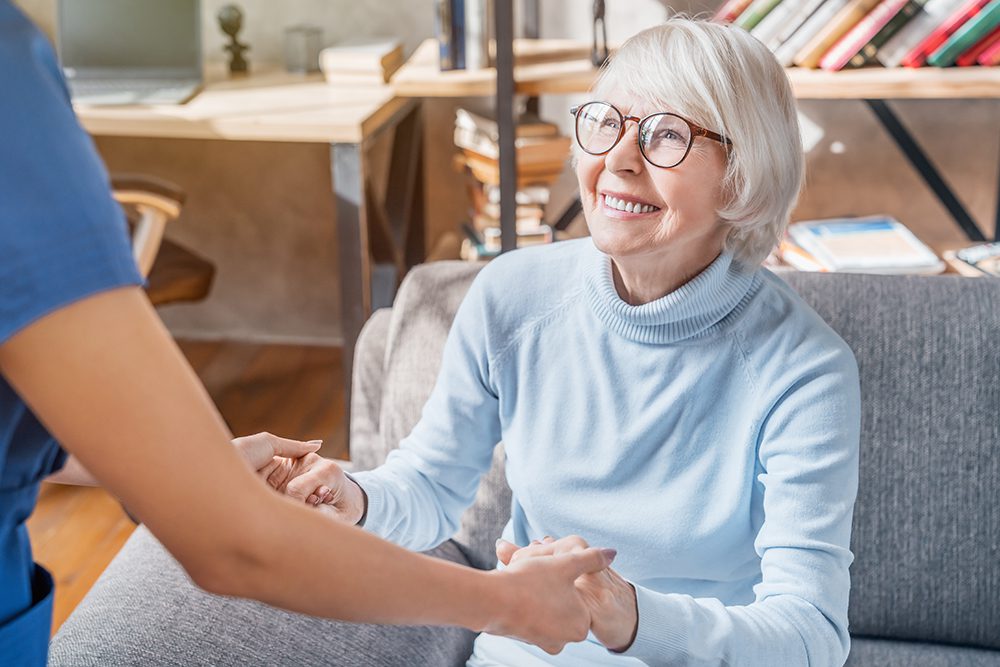 a smiling woman being helped out of her seat by a healthcare worker